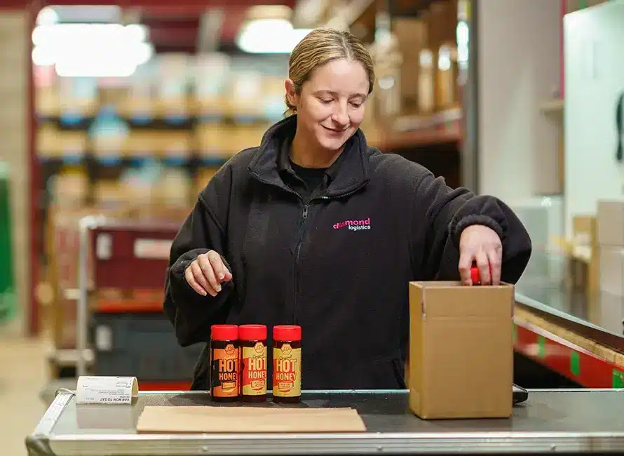 A Diamond Logistics employee wraps bottles of hot sauce in a warehouse