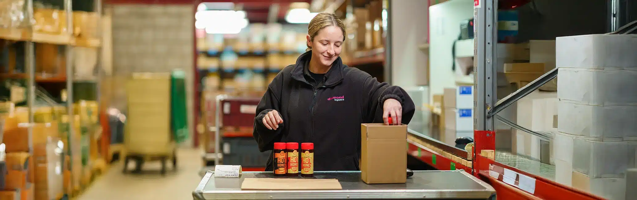 A Diamond Logistics employee wraps bottles of hot sauce in a warehouse