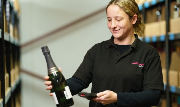 A female Diamond Logistics warehouse worker scans a bottle of champagne